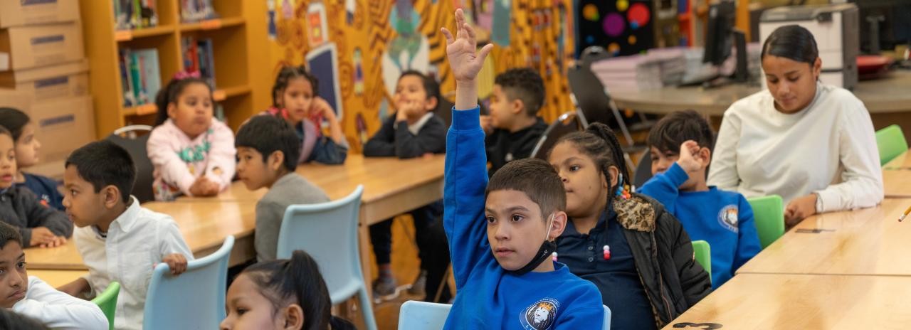 A student raises his hand in a classroom.