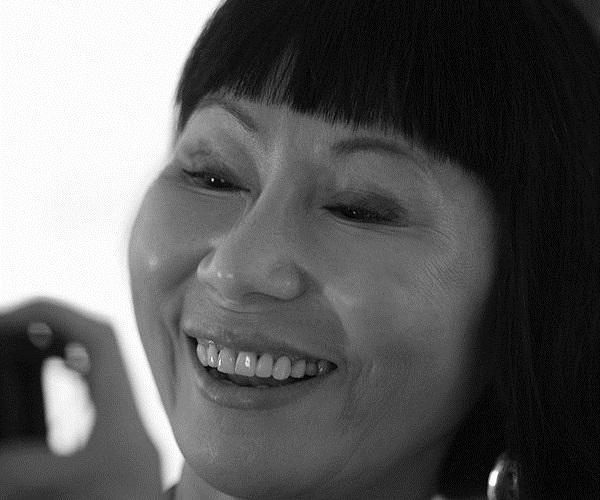 black and white photo of an Asian woman's face, smiling but looking off camera