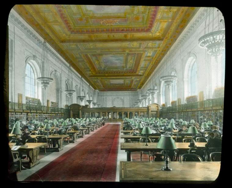 large room with rows and rows of desks and an ornate ceiling 