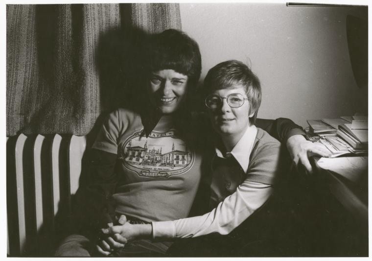 two women on couch holding hands
