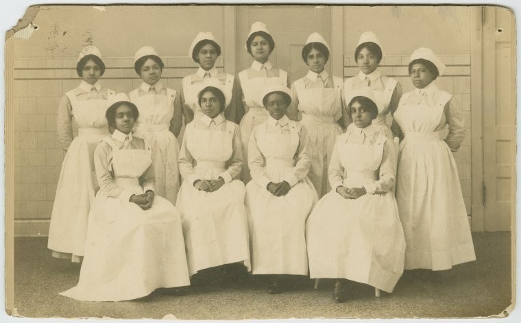 11 nurses in uniform posing for group portrait