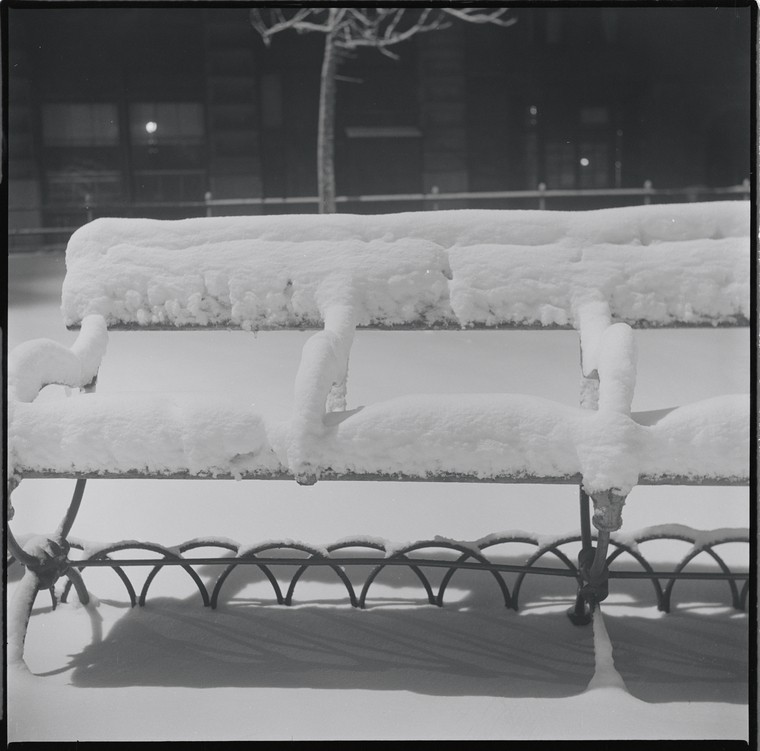 park bench covered in snow at night