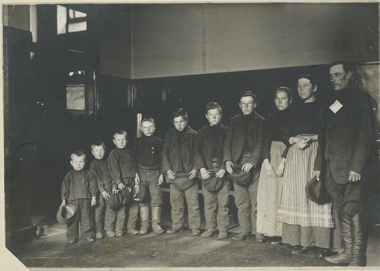 eight children lined up by height next to their parents