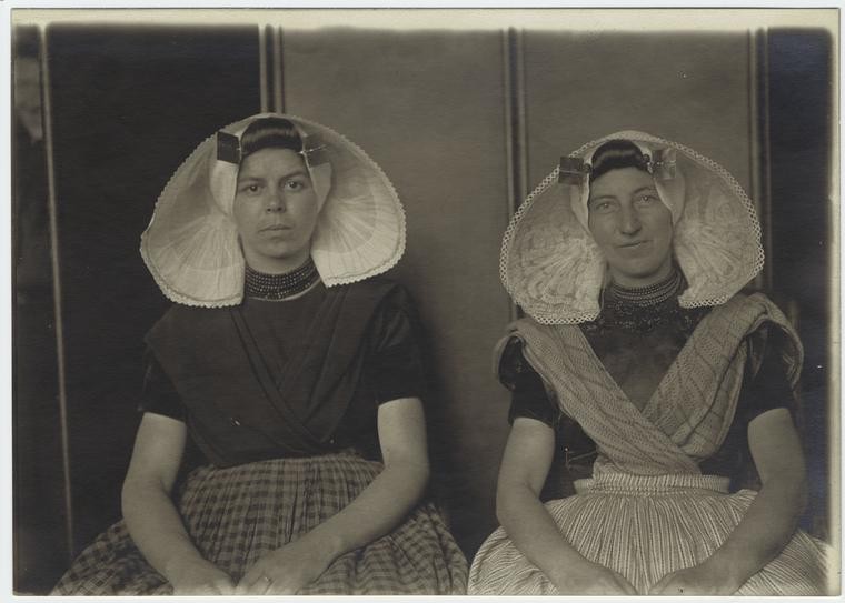 two women, seated, wearing traditional Dutch headwear