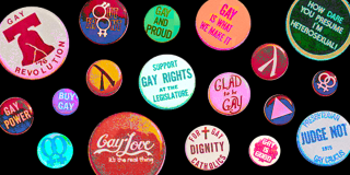 Colorful lapel pins with positive messages including "Gay Power" and "Gay Revolution" against a black background.