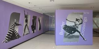 Photograph of exhibition entrance featuring purple walls with 5 photographs of dancers.