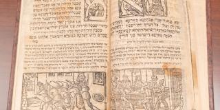 Open book with Hebrew text. A woodcut image on each page; right side a group of men at a table.