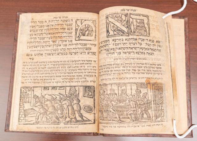 Open book with Hebrew text. A woodcut image on each page; right side a group of men at a table.
