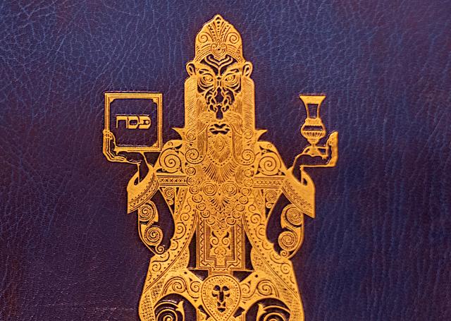 Gold design on blur leather; a lion-faced man holding a jar and a book with Hebrew text.