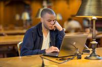 man sits at study room table and reads laptop