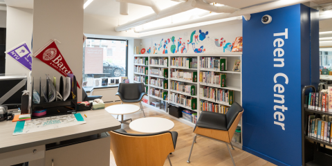Interior of the Macomb's Bridge Library Teen Center, featuring lounge chairs, shelves of books, and a colorful wall mural.